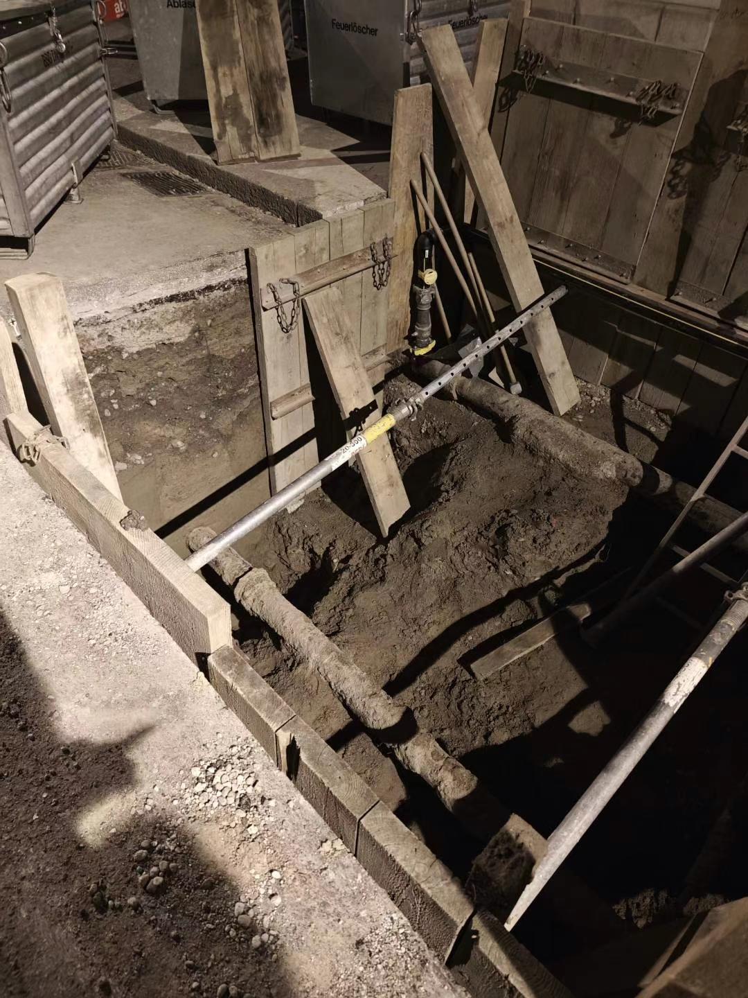 Night-time street trench with timber shoring and service pipes